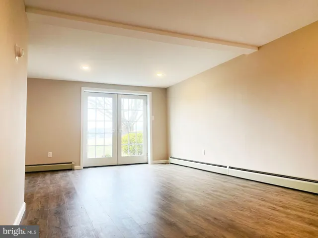 an empty room with wooden floor and windows with curtains