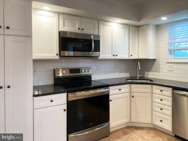 a kitchen with white cabinets and appliances