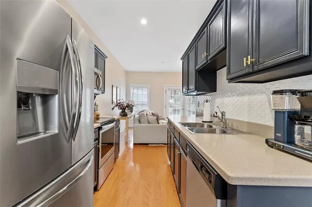 a kitchen with stainless steel appliances granite countertop a sink a stove and a refrigerator