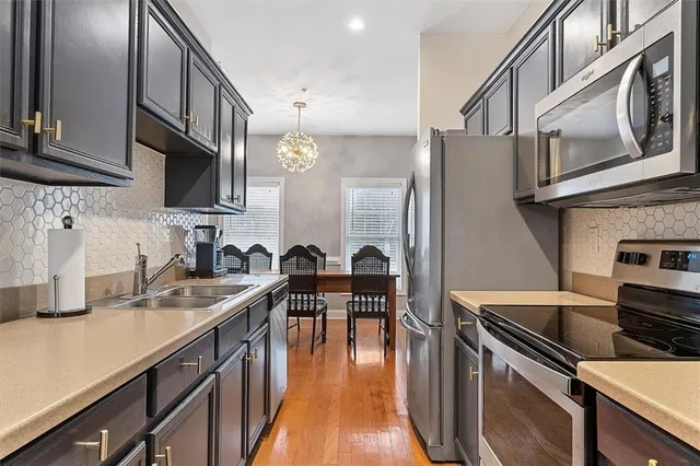 a kitchen with stainless steel appliances granite countertop a sink a stove and a wooden floors