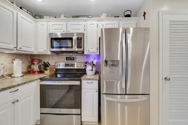 a kitchen with stainless steel appliances granite countertop a refrigerator sink and microwave
