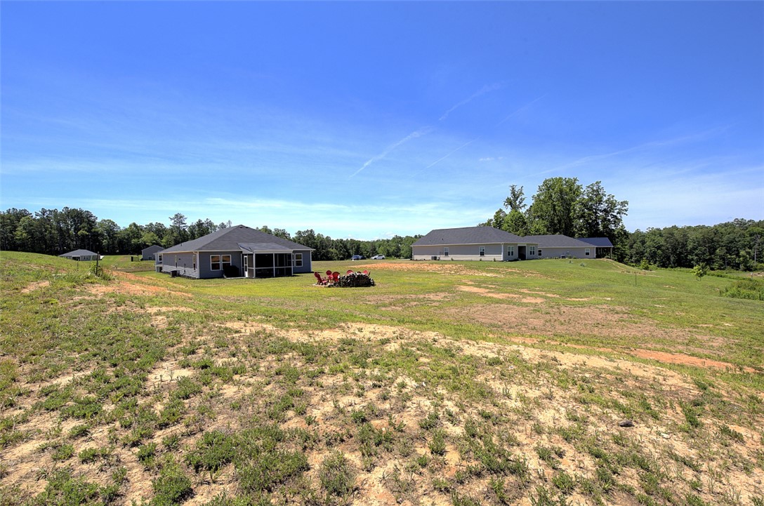 408 Chadwick Lane Walhalla, SC 29691 - Photo 34 of 44 A tranquil rural vista unfolds with homes nestled against a backdrop of mature trees and an expansive, clear blue sky.