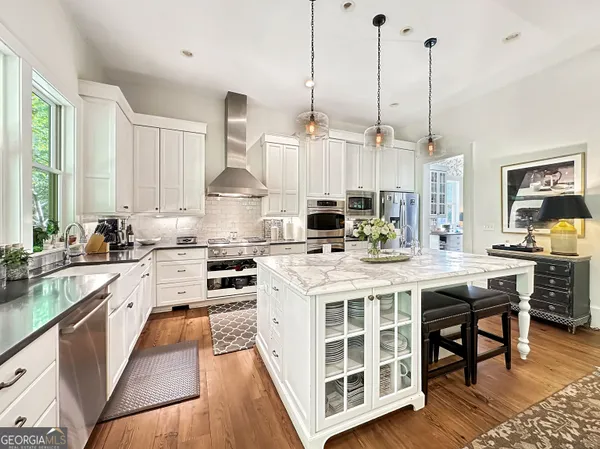 a large kitchen with kitchen island stainless steel appliances a table chairs sink and wooden floor