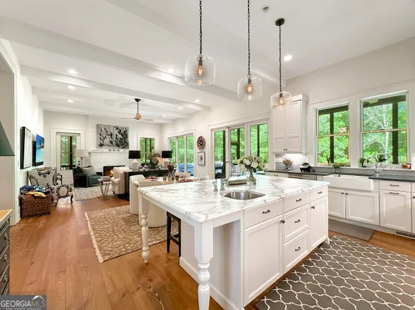 a large white kitchen with lots of counter space a sink appliances and a large window