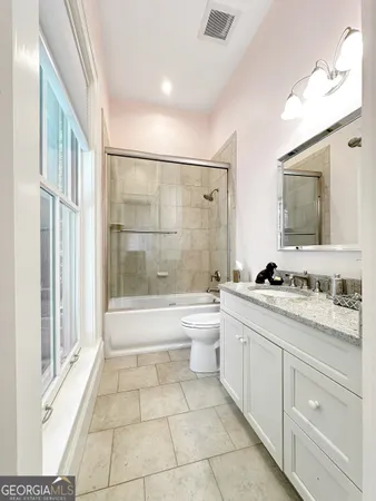 a bathroom with a granite countertop sink a toilet a mirror and bathtub