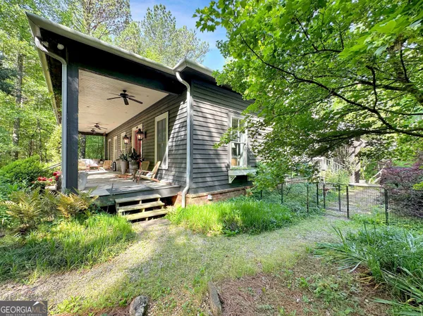 a backyard of a house with lawn chairs plants and large tree