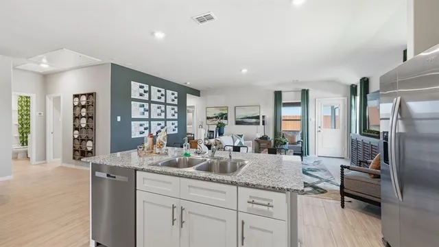 a kitchen with stainless steel appliances granite countertop a refrigerator a stove top oven a sink dishwasher and white cabinets with wooden floor