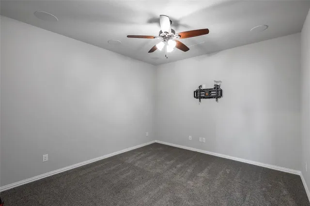 an empty room with a chandelier fan and windows