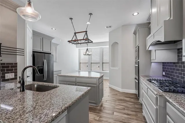 a kitchen with stainless steel appliances granite countertop a sink a stove and a refrigerator