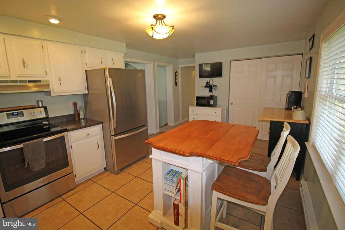 6603 South Clifton Road Frederick, MD 21703 - Photo 14 of 21 a kitchen with stainless steel appliances granite countertop a refrigerator a stove a sink dishwasher and a stove with wooden floor