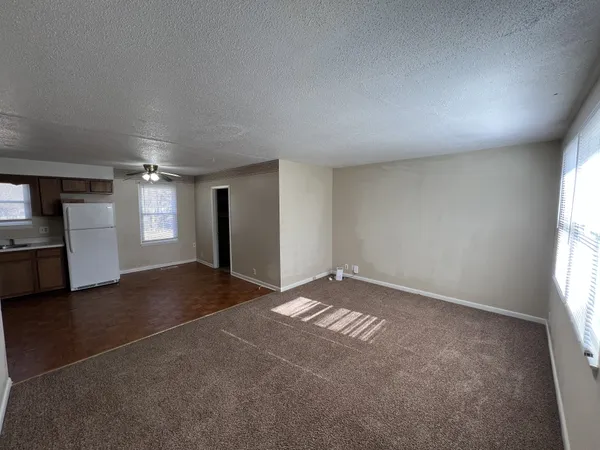 an empty room with windows and refrigerator