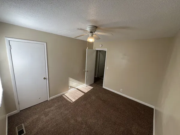 an empty room with a ceiling fan and a window