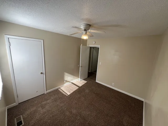 an empty room with a ceiling fan and a window