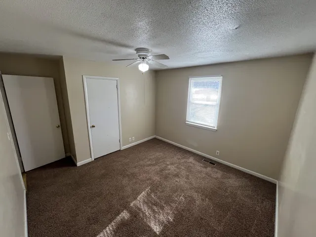 an empty room with windows and fan