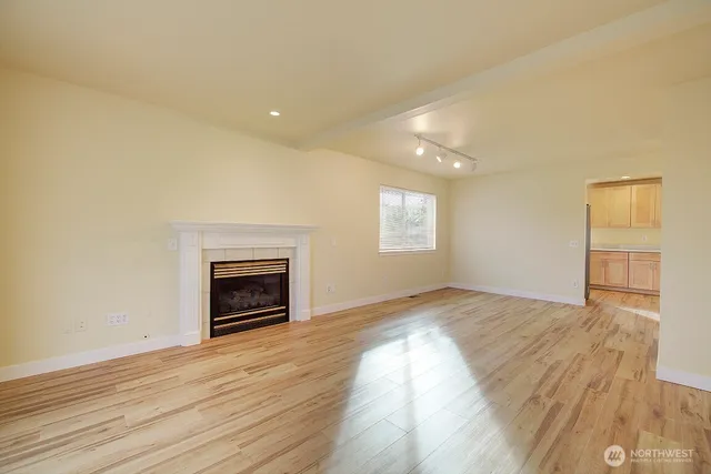 an empty room with wooden floor fireplace and windows
