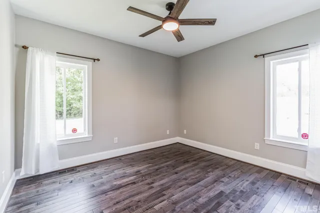 a view of an empty room with wooden floor and furniture