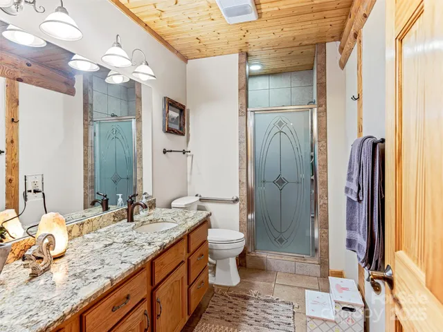 a bathroom with a granite countertop sink a toilet and shower