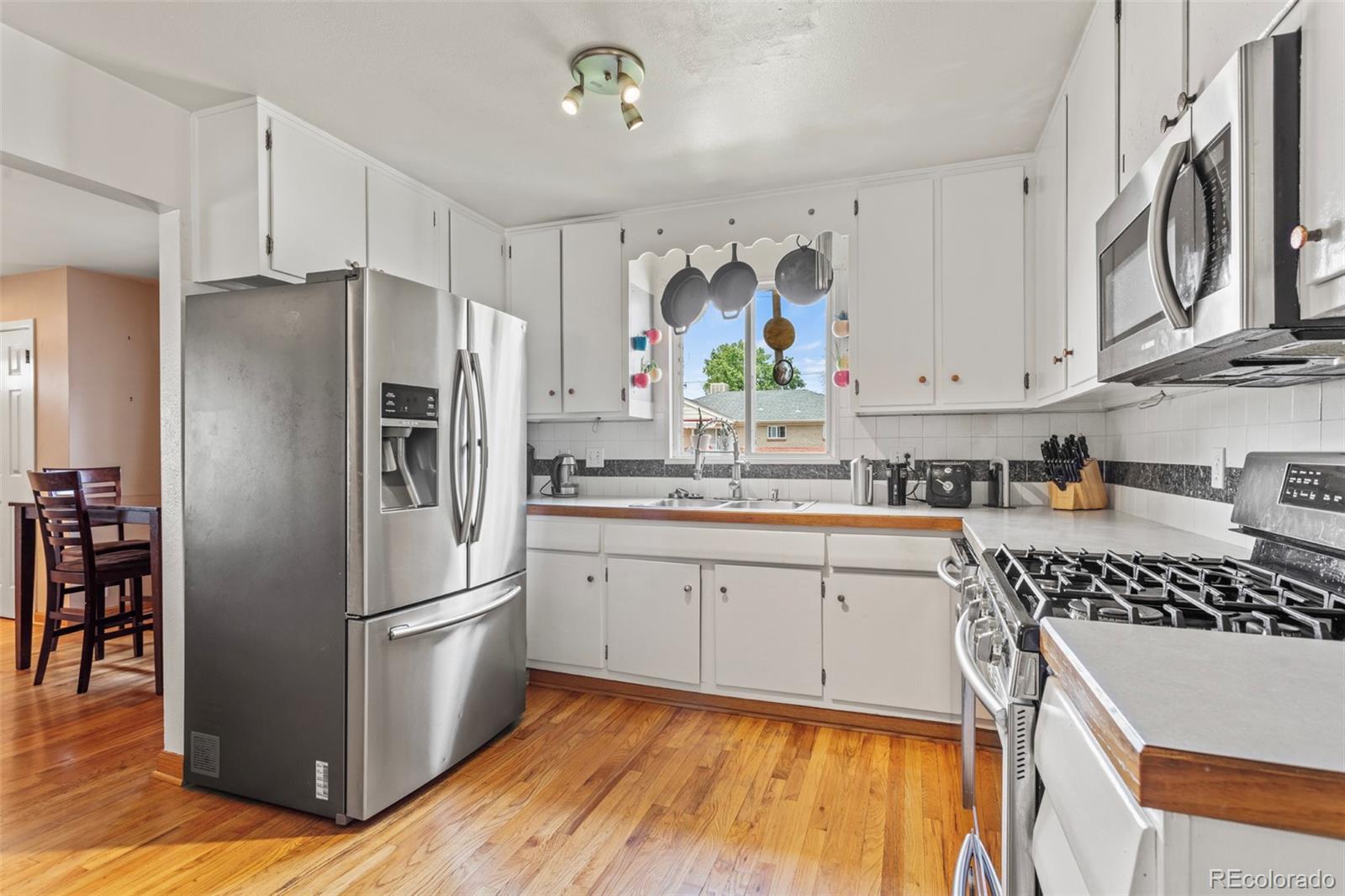 7296 Raritan Street Denver, CO 80221 - Photo 7 of 23 a kitchen with stainless steel appliances a refrigerator sink and cabinets
