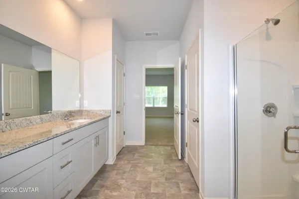 a bathroom with a granite countertop sink mirror and a shower