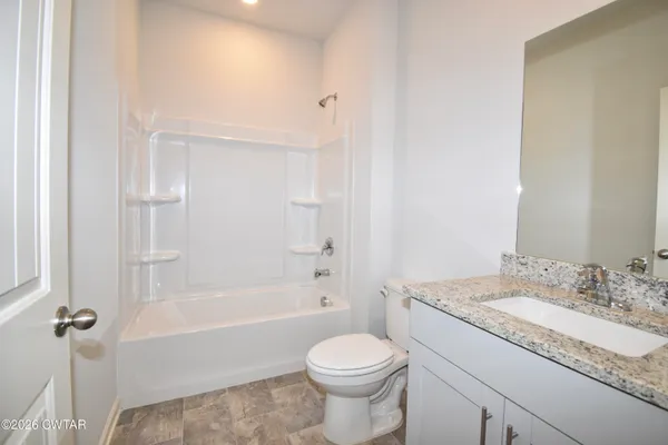 a bathroom with a granite countertop toilet a sink and a bathtub