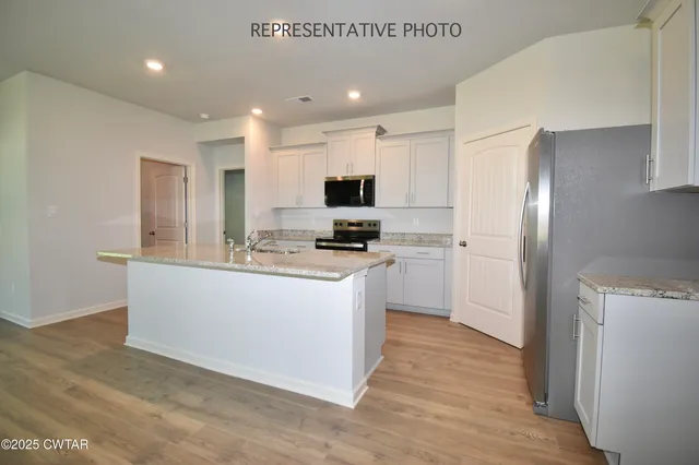 a kitchen with granite countertop a refrigerator stove top oven and cabinets