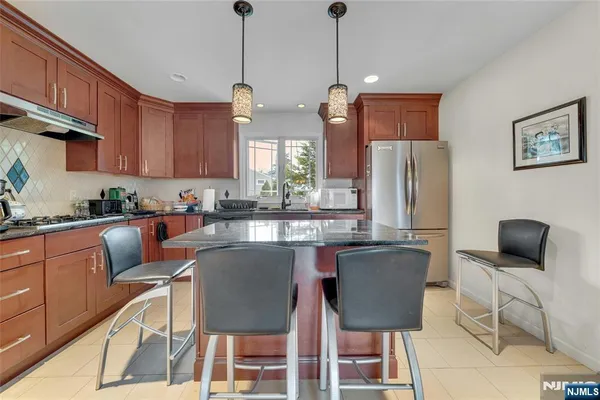 a kitchen with stainless steel appliances granite countertop a refrigerator a stove a sink dishwasher a dining table and chairs with wooden floor