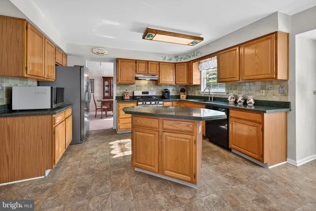 a kitchen with stainless steel appliances granite countertop a stove a sink dishwasher a refrigerator and white cabinets with wooden floor