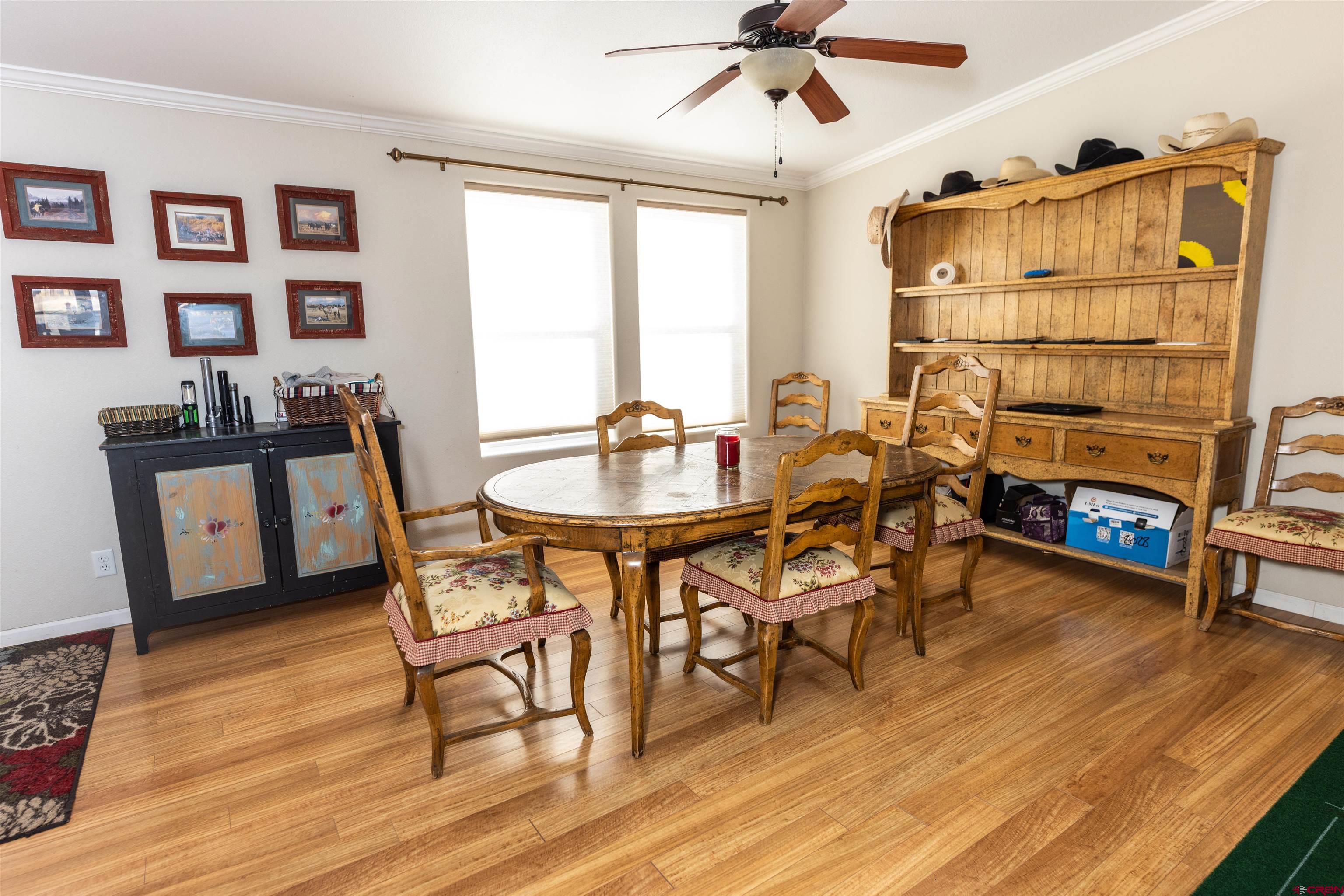 2716 Threemile Road Alamosa, CO 81101 - Photo 13 of 45 a dining room with wooden floor a chandelier a wooden table and chairs