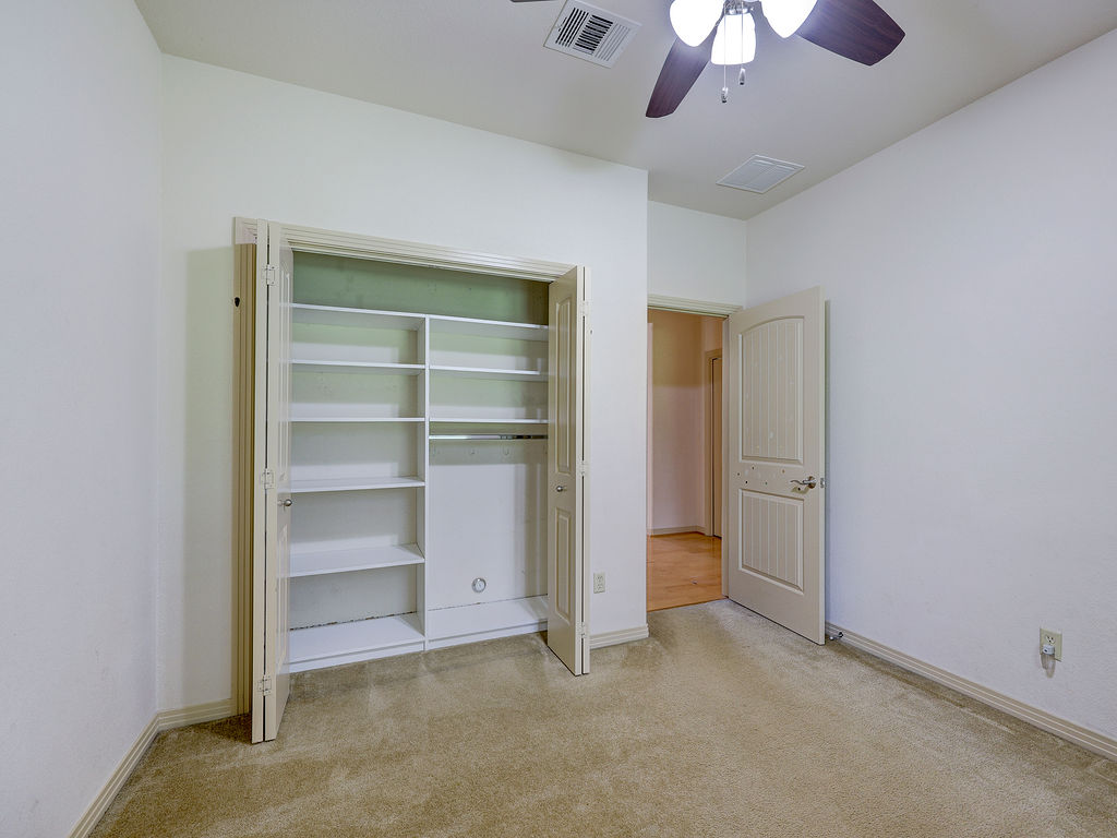 9707 Anderson Mill Road, Unit 22 Austin, TX 78750 - Photo 23 of 39 A comfortable bedroom features carpet flooring and a built-in closet with shelves.