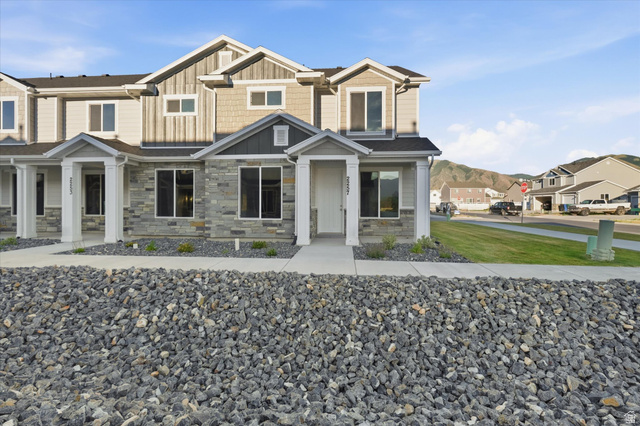 2257 South 1090 West, Unit 74 Nibley, UT 84321 - Photo 23 of 40 Townhome exterior featuring stone veneer, vertical siding, and shake accents