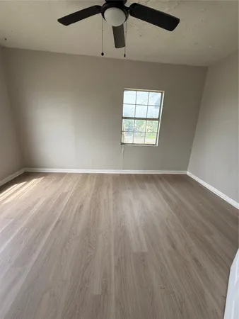an empty room with wooden floor cabinet and windows