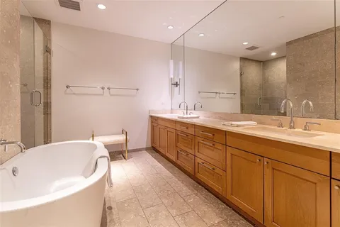 a spacious bathroom with a double vanity sink a large mirror and a bathtub