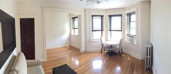 a view of a hallway with wooden floor and a living room
