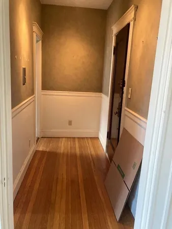 a view of an empty room with window and wooden floor