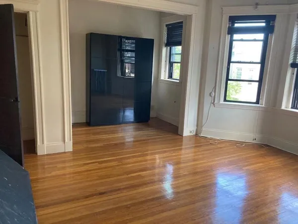 a view of an empty room with wooden floor and a window