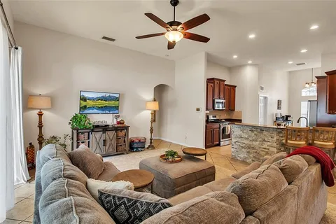 a living room with furniture kitchen view and a wooden floor