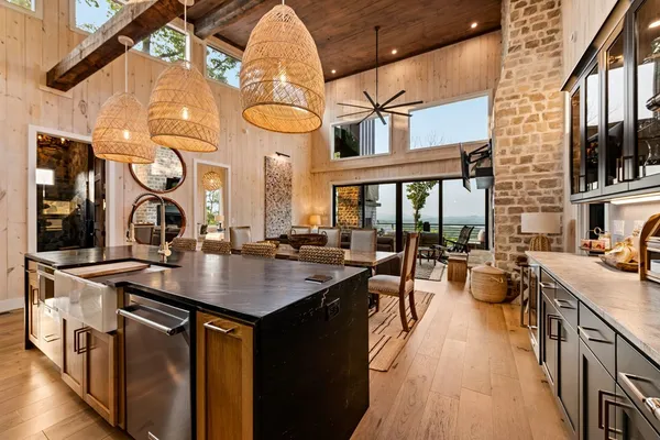 a kitchen with stainless steel appliances kitchen island granite countertop a refrigerator a stove and a sink with wooden floor