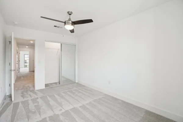 an empty room with a white cabinet and a ceiling fan