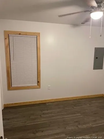 an empty room with wooden floor fan and windows