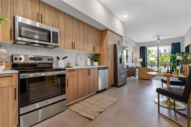 a kitchen with stainless steel appliances kitchen island granite countertop a stove top oven a sink dishwasher a dining table and chairs with wooden floor
