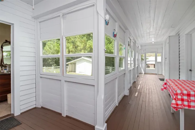 a view of a hallway with wooden floor and windows