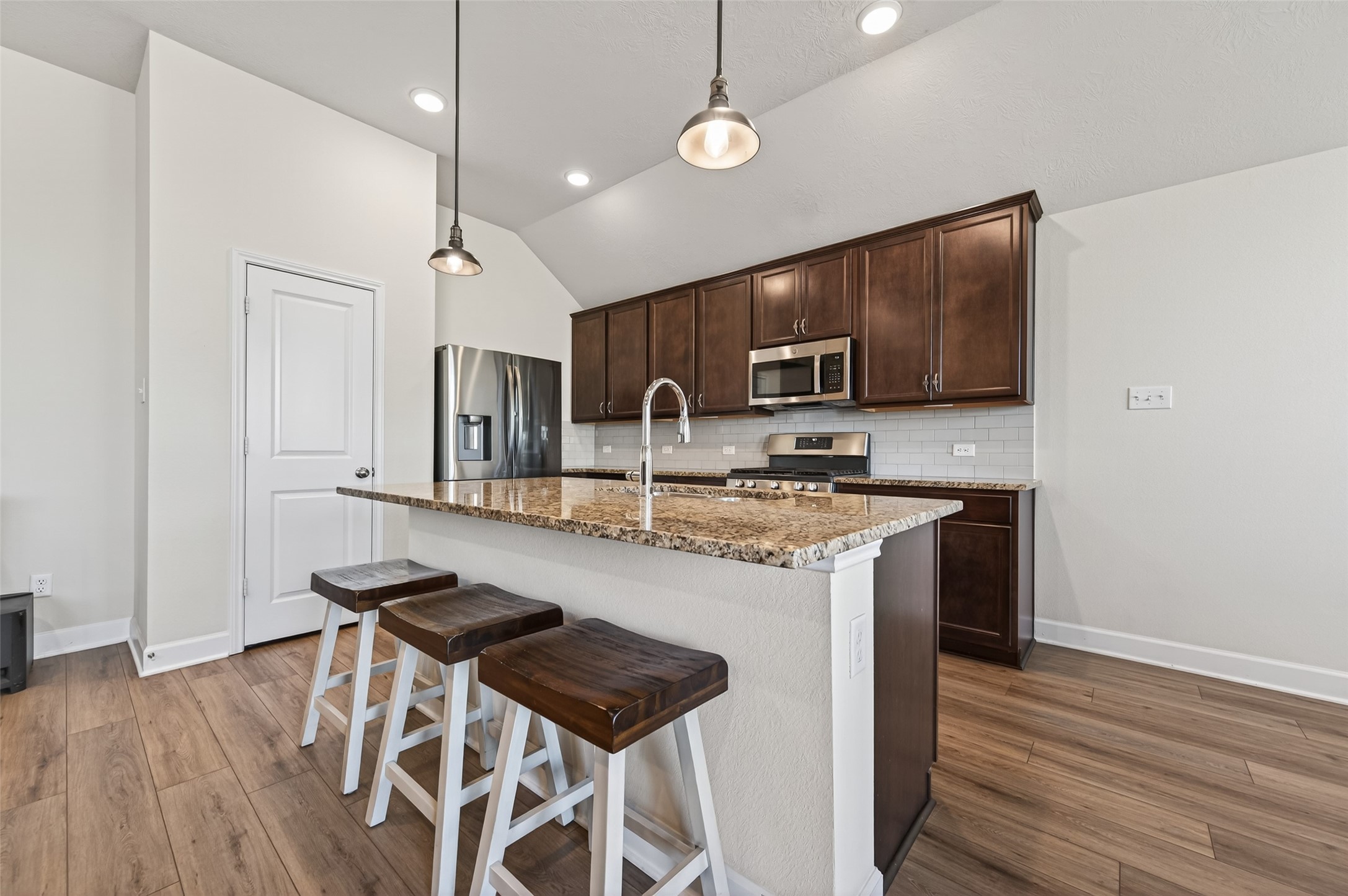 917 Farm Path Brenham, TX 77833 - Photo 11 of 43 a kitchen with stainless steel appliances granite countertop a sink a stove a refrigerator and a microwave with wooden floor