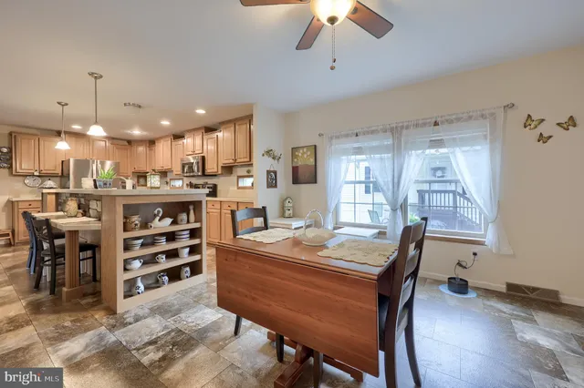 a room with stainless steel appliances kitchen island granite countertop a table chairs and a refrigerator