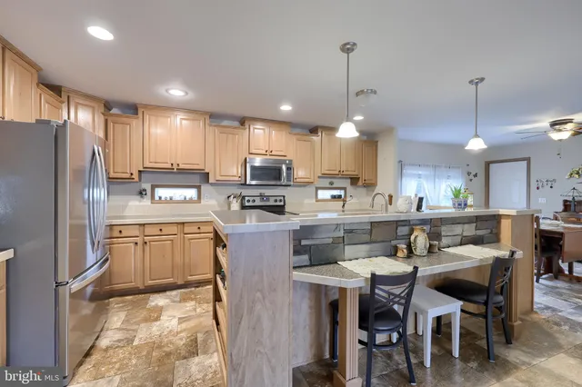 a kitchen with kitchen island granite countertop a sink a center island stainless steel appliances and cabinets