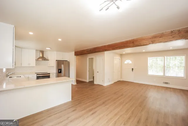 a large white kitchen with kitchen island a sink wooden floor and a refrigerator