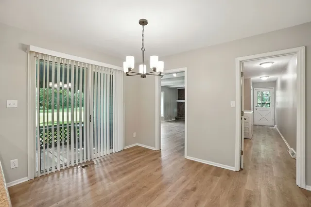 a view of a hallway with wooden floor and chandelier