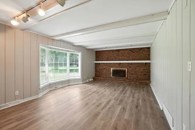 an empty room with wooden floor fireplace and windows