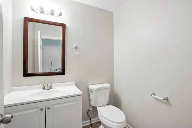 a bathroom with a toilet sink vanity and mirror