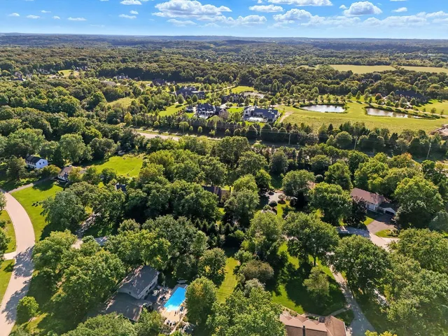 an aerial view of residential houses with outdoor space and trees