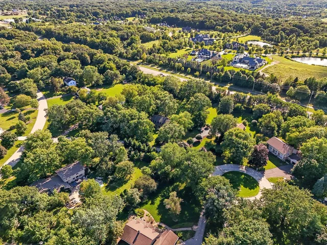 an aerial view of residential house with outdoor space and trees all around